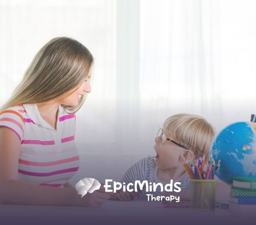 Therapist smiling and engaging with young boy during ABA therapy activity.