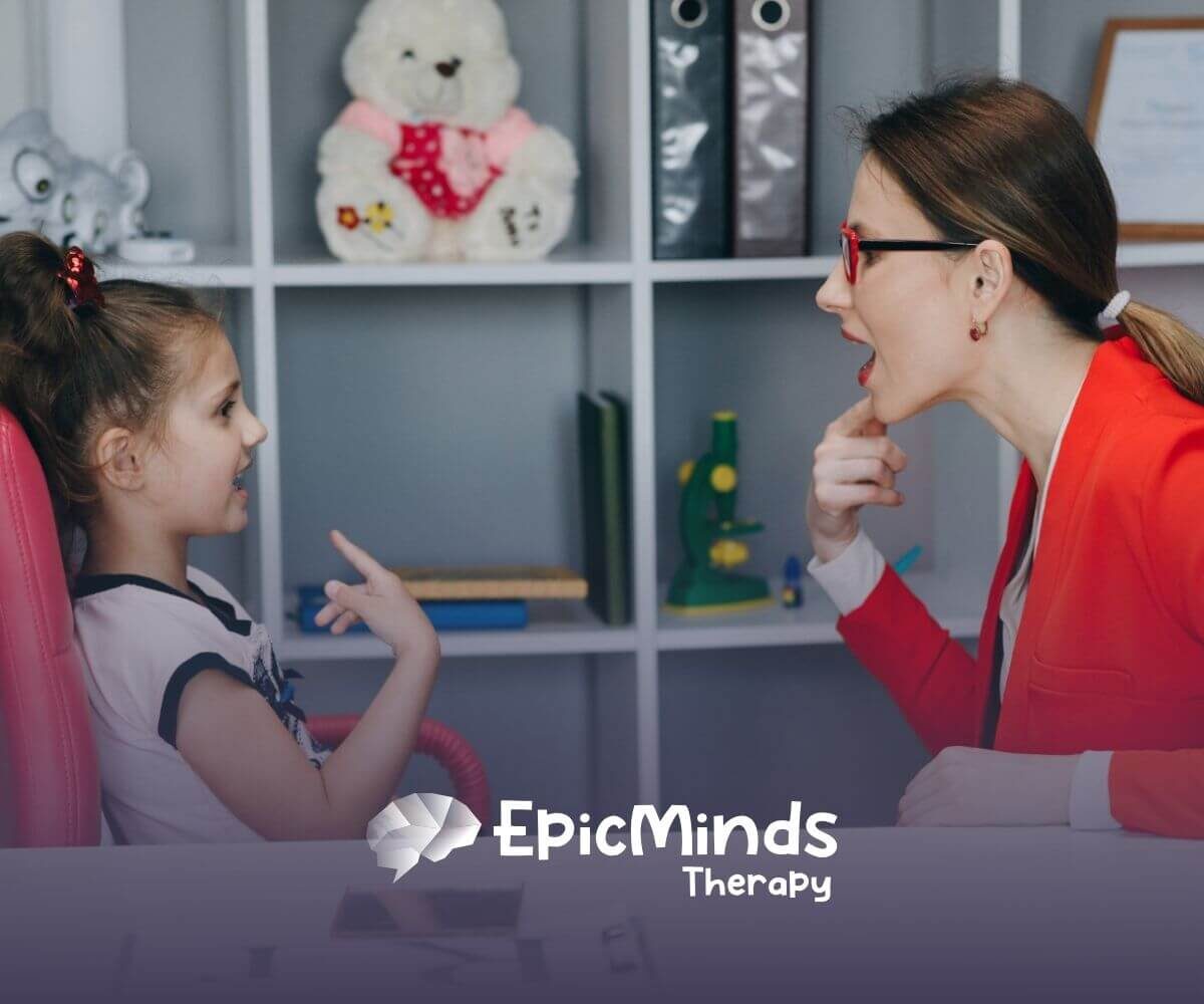 Therapist helping a young girl practice speech sounds during ABA therapy session.