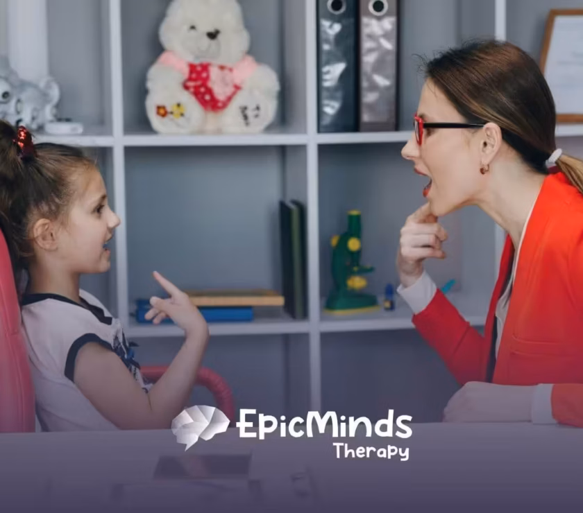Therapist helping a young girl practice speech sounds during ABA therapy session.