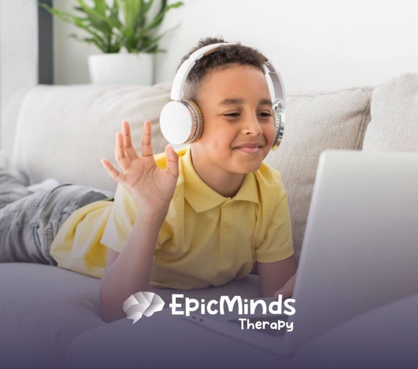 Child with autism wearing headphones waving at laptop while lying on a couch
