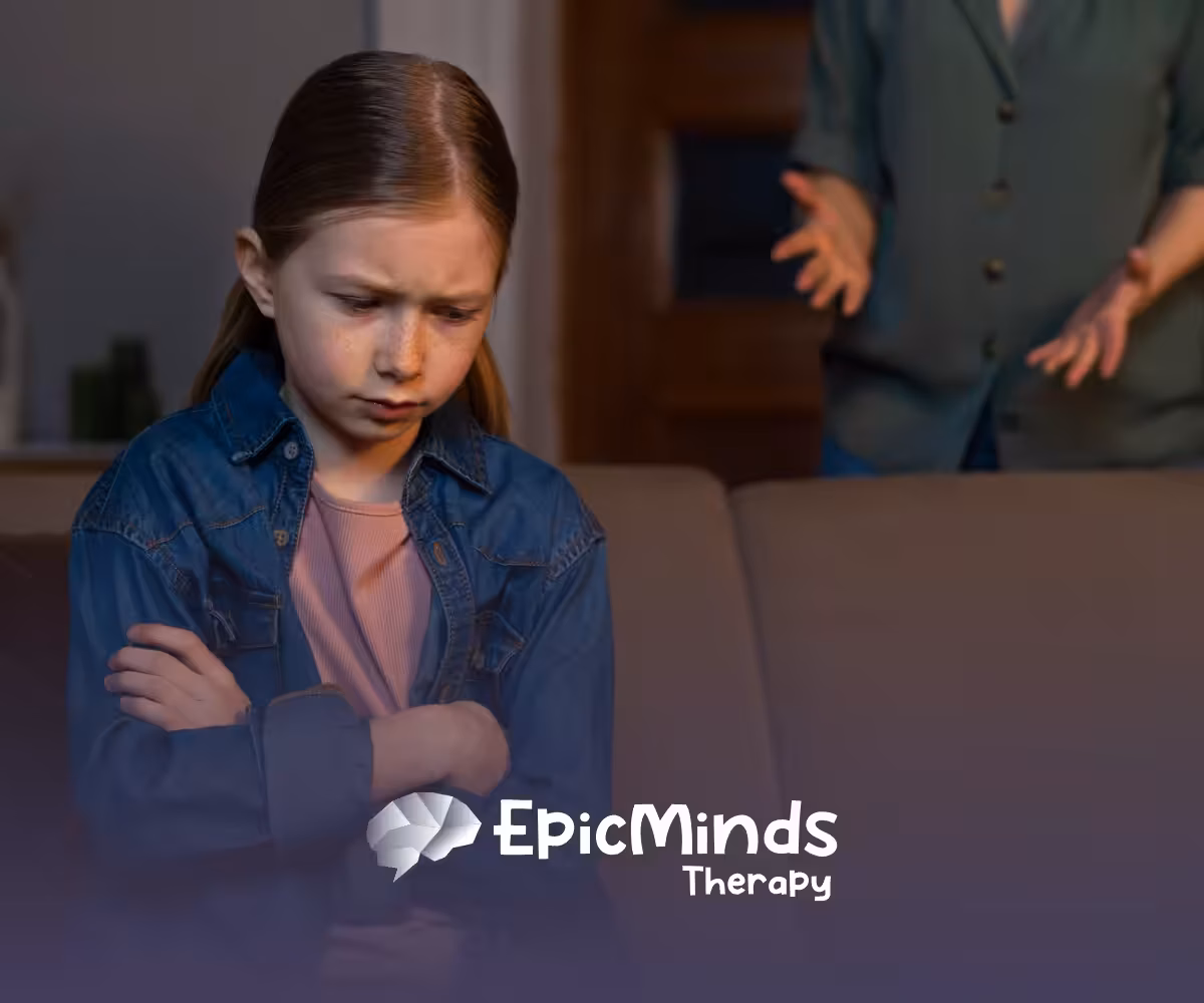 A kid with a frowning face sitting on a couch