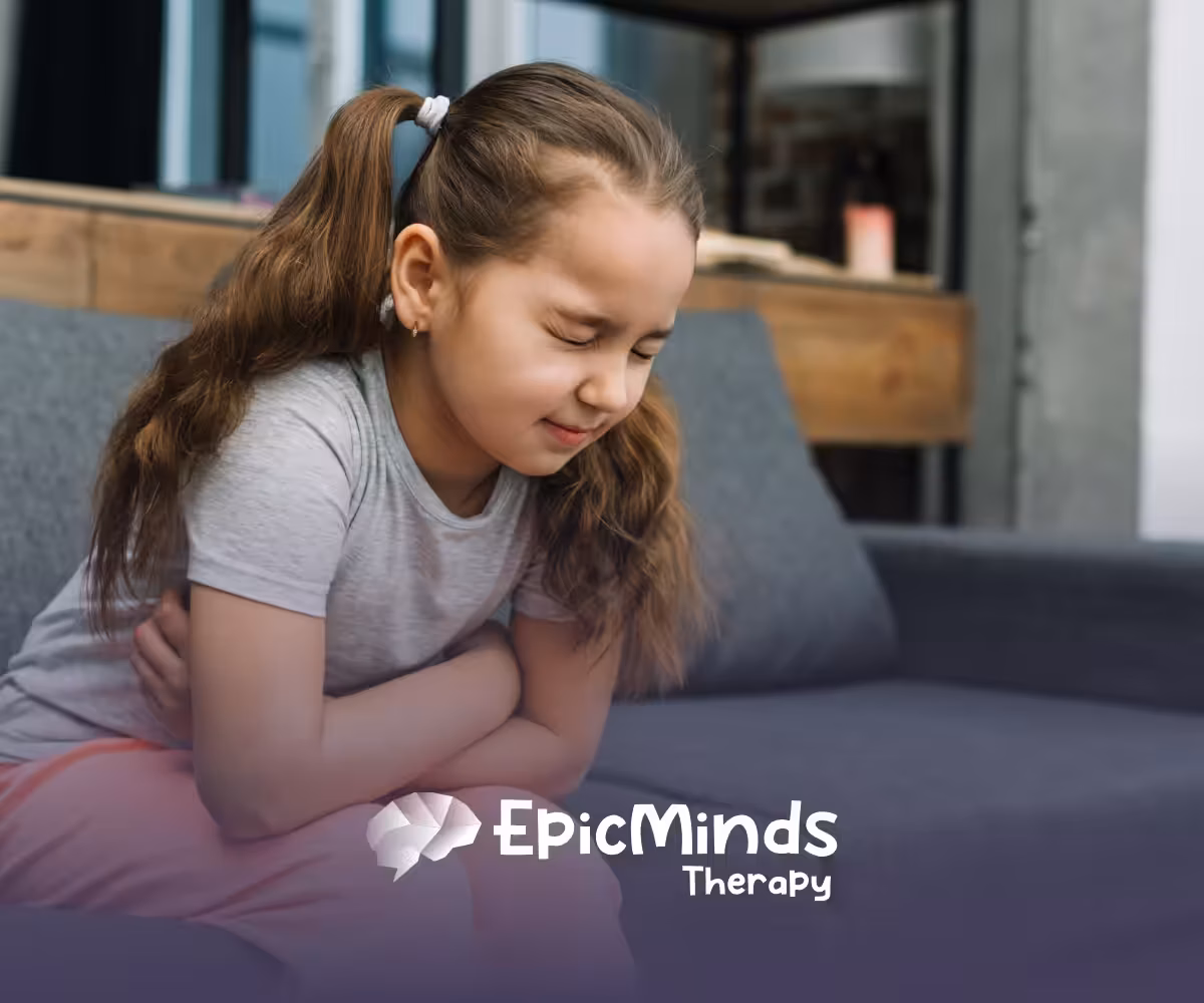 A child sitting on a bench, with her arms wrapped around her stomach