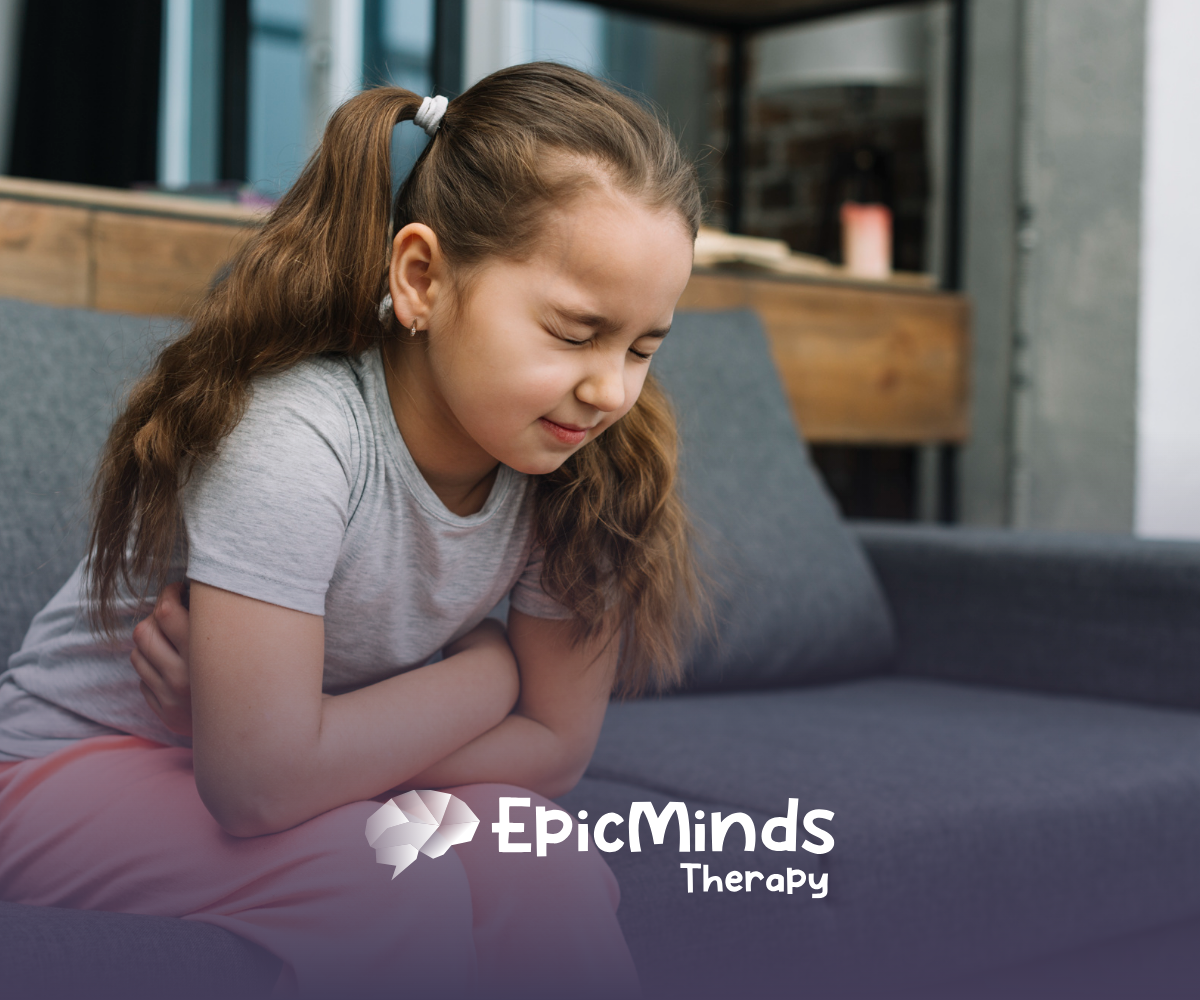 A child sitting on a bench, with her arms wrapped around her stomach