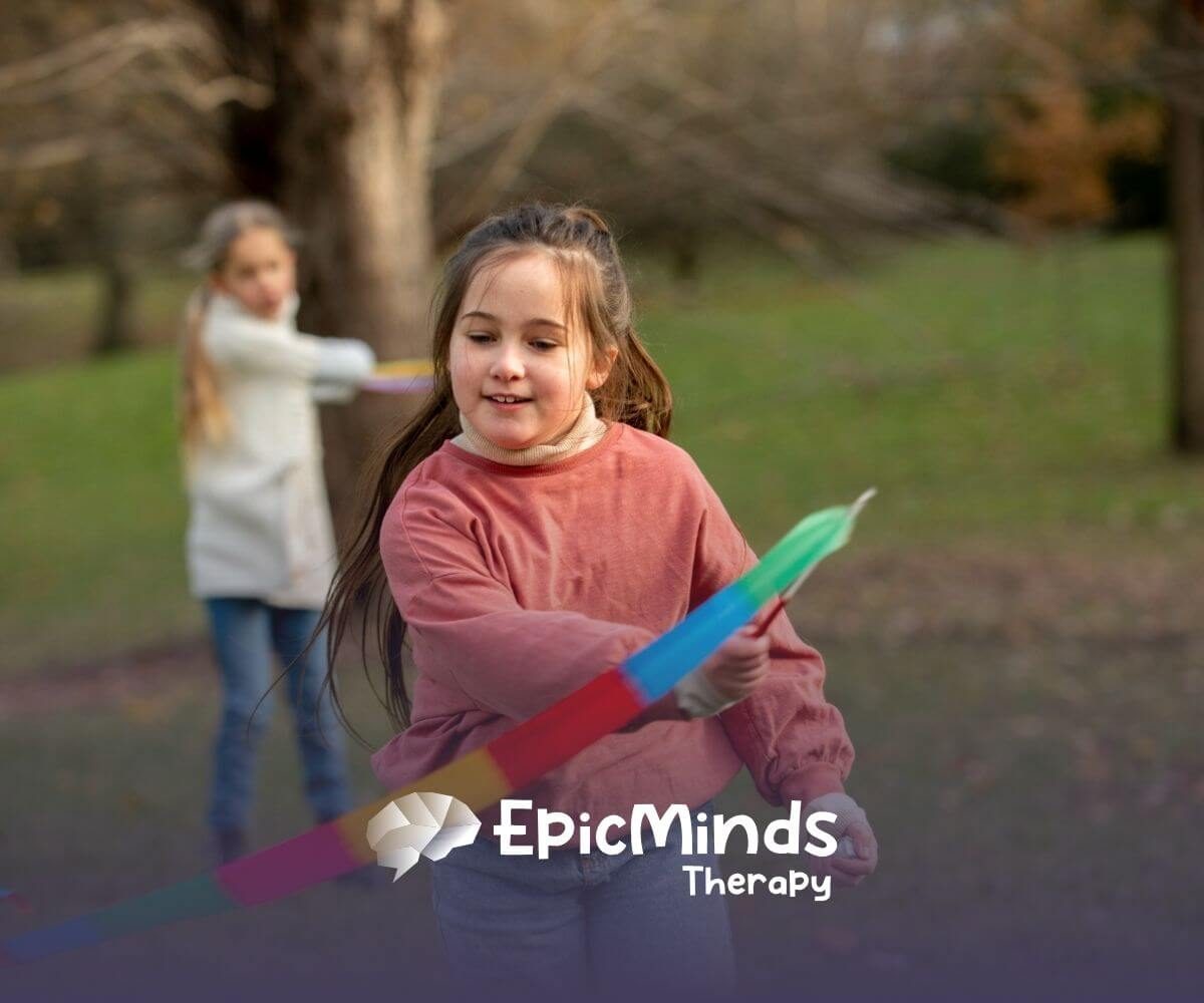 Girl with autism happily playing with a colorful ribbon outdoors in a park in NC.
