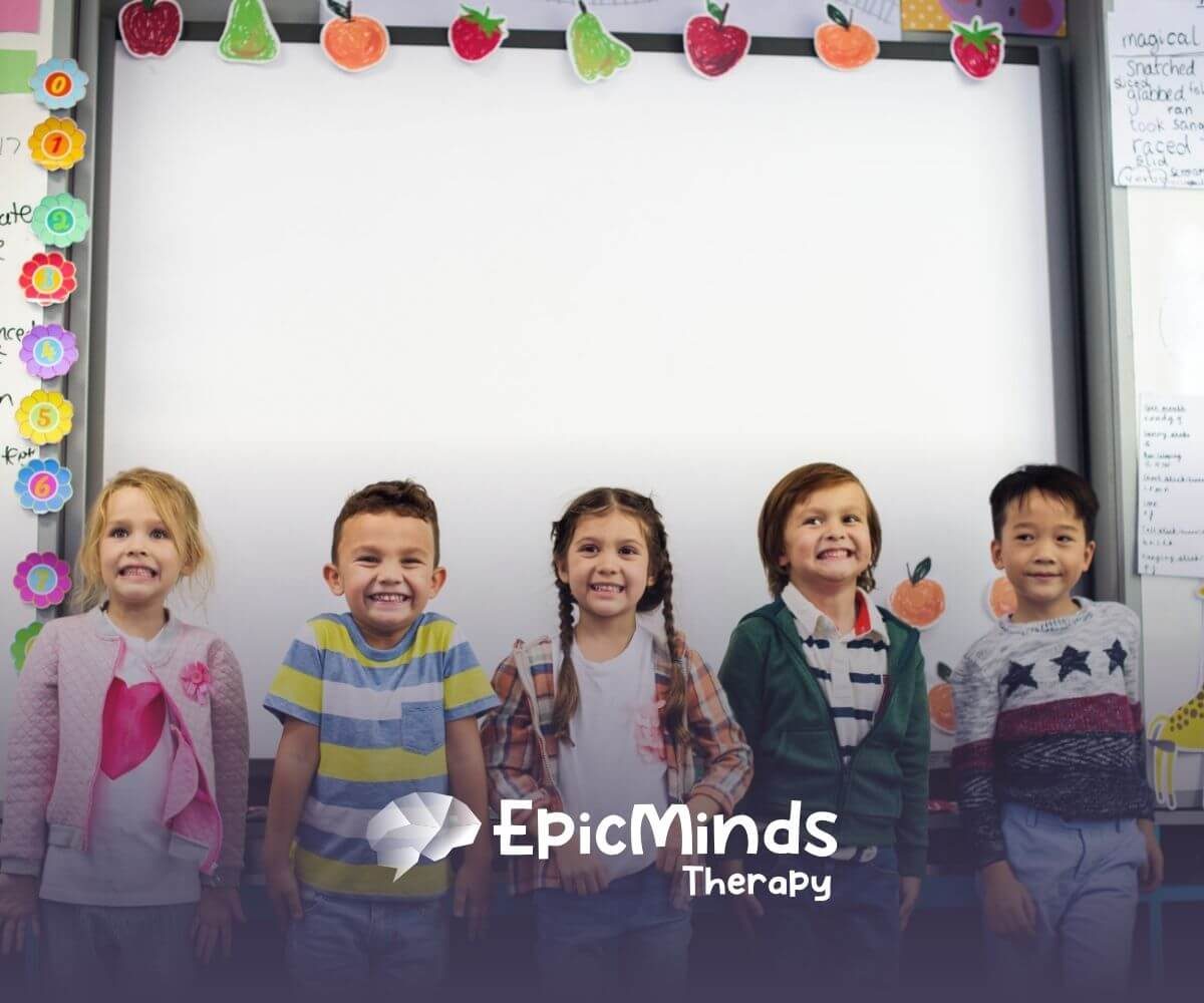 Five children with autism smiling together in a classroom.