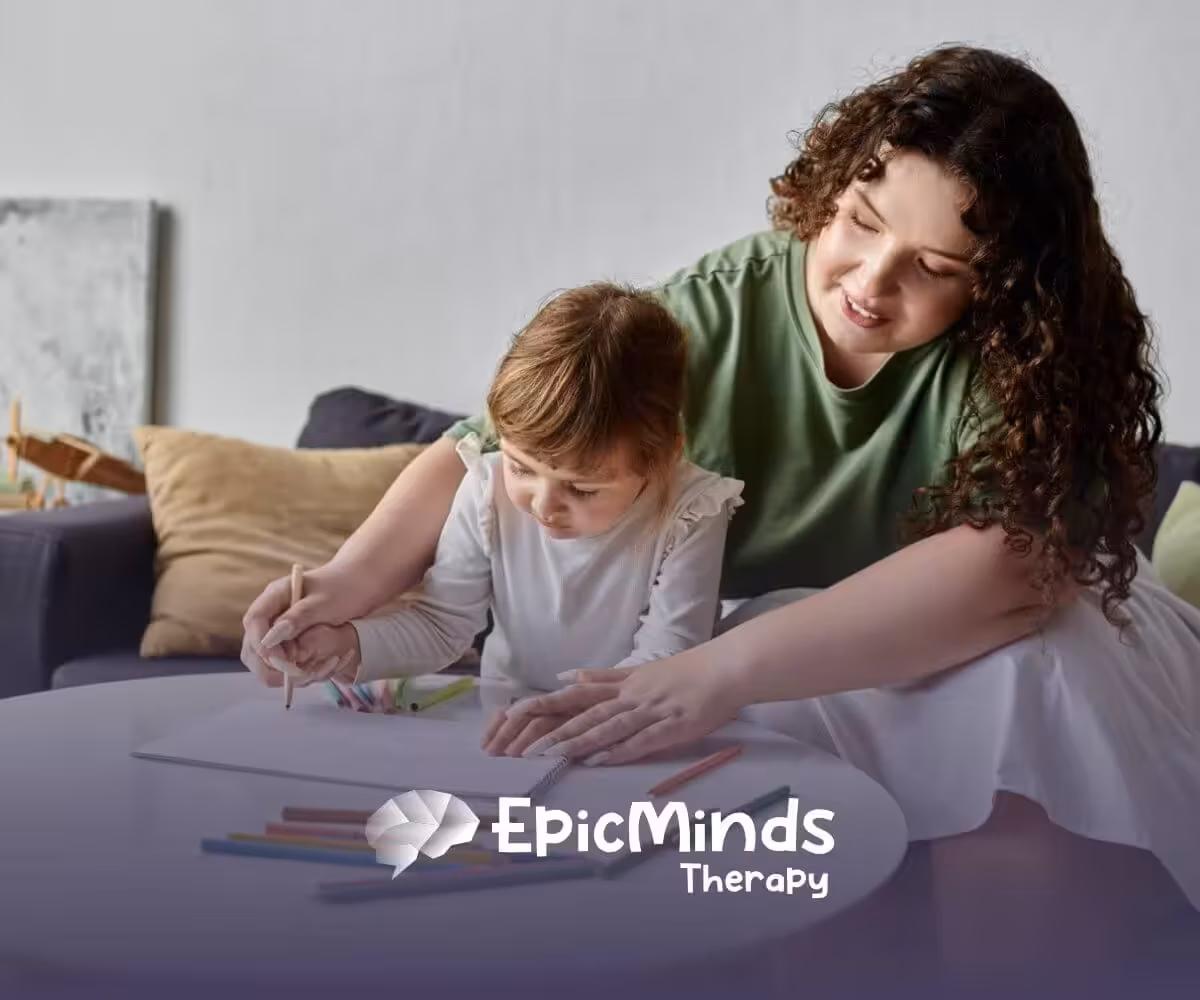 A BCBA helping a girl with autism color in a drawing, with crayons scattered around the table.