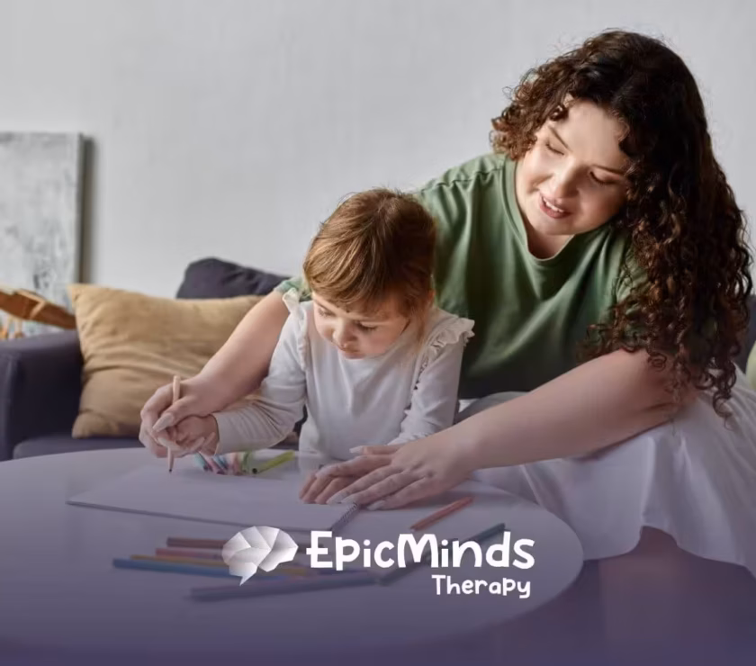 A BCBA helping a girl with autism color in a drawing, with crayons scattered around the table.