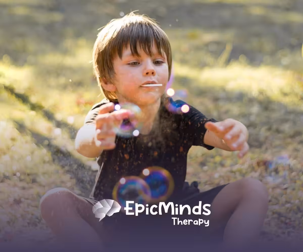 Young boy with autism playing with bubbles outdoors on a sunny day.