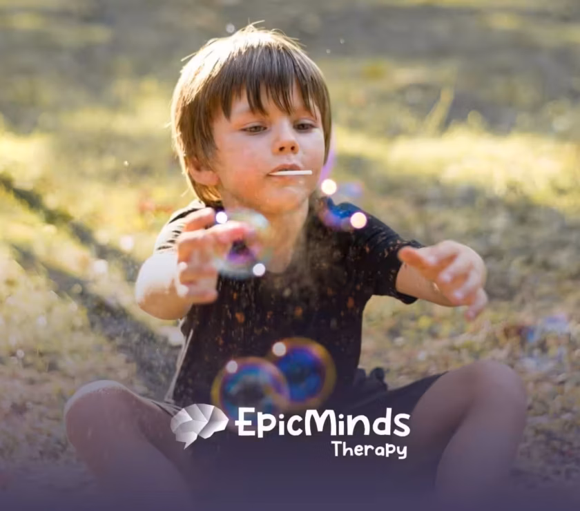 Young boy with autism playing with bubbles outdoors on a sunny day.