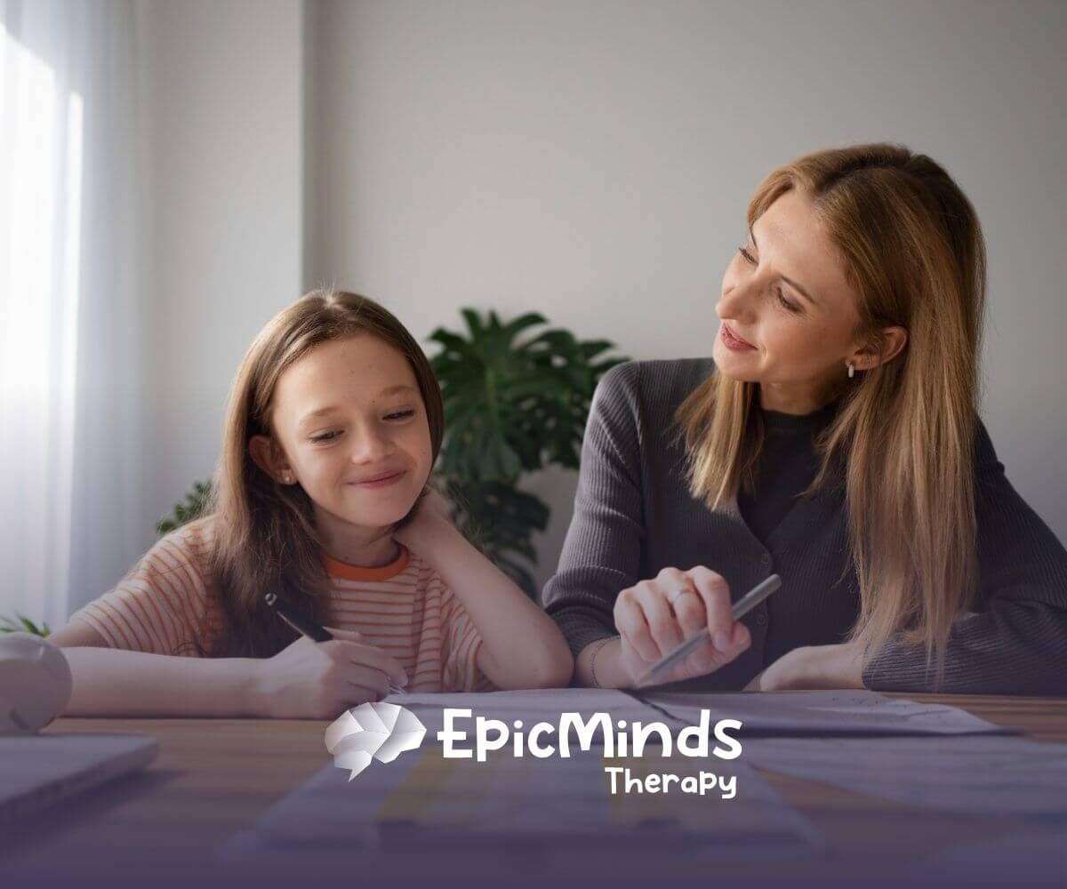 A BCBA and girl with autism sitting at a desk during ABA therapy session.
