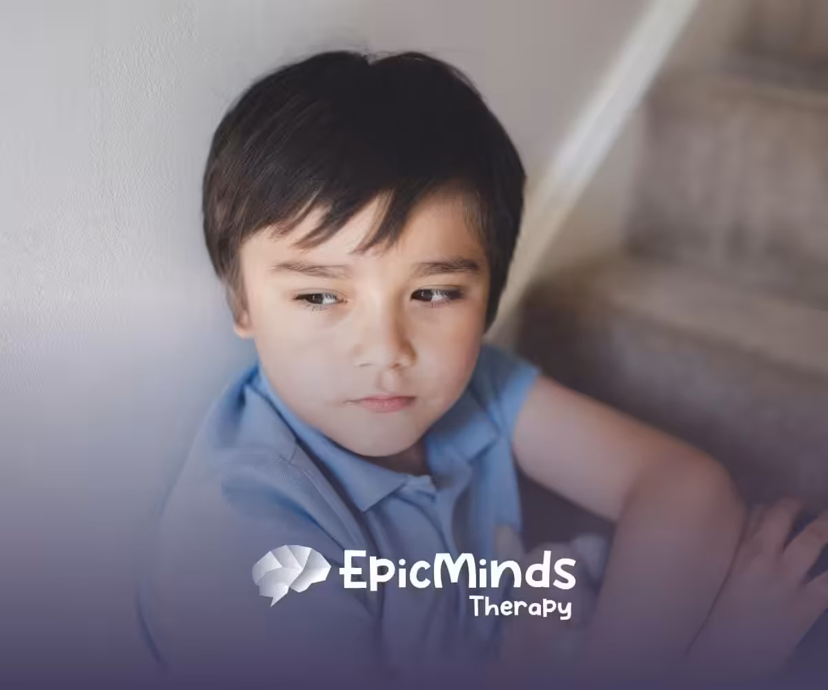 A boy with severe autism sitting on stairs, looking pensive with a stuffed animal in his lap.