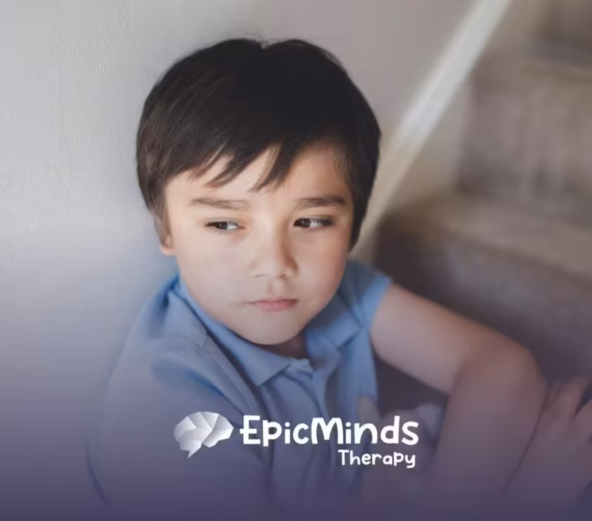 A boy with severe autism sitting on stairs, looking pensive with a stuffed animal in his lap.