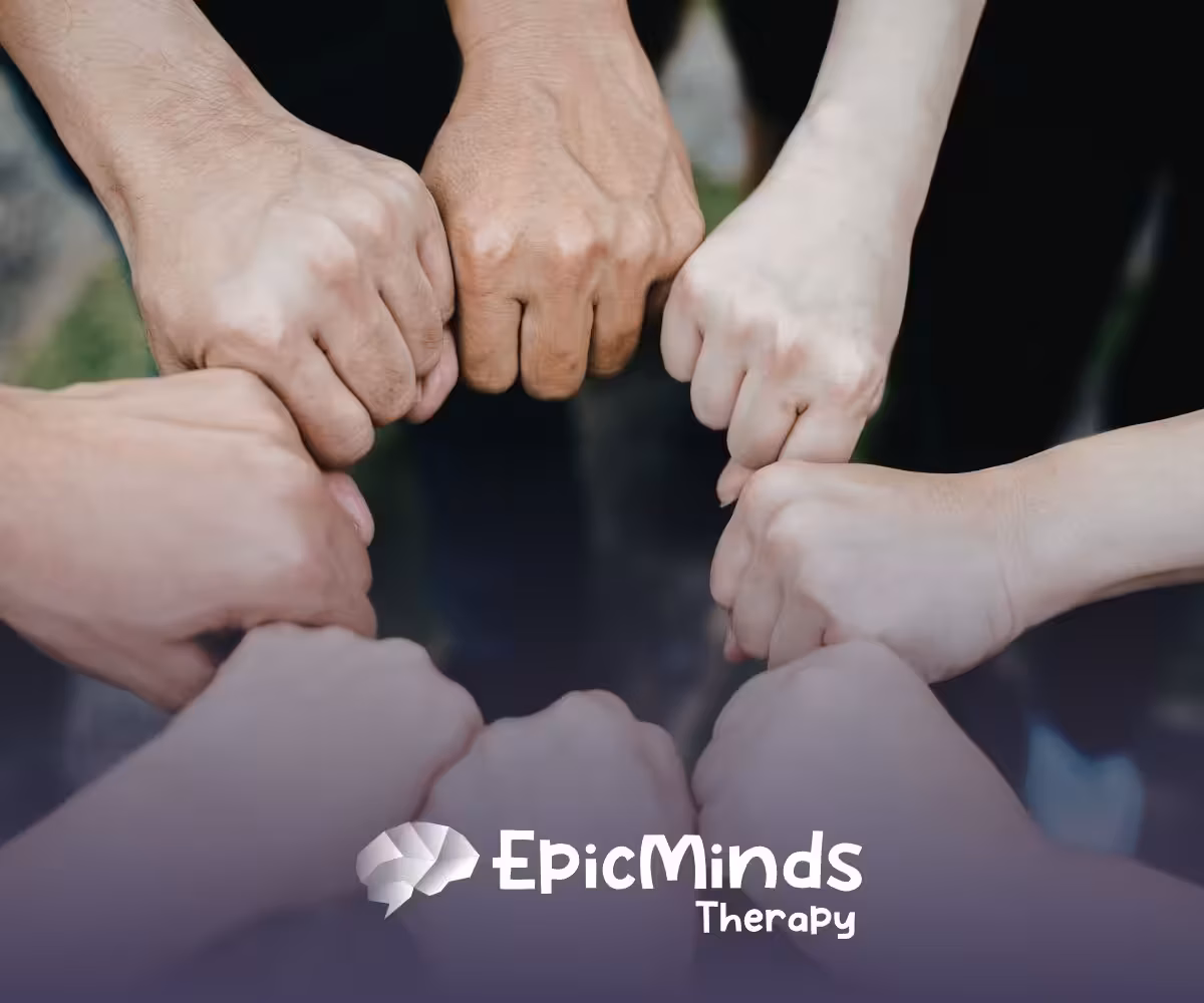 Seven hands form a circle with fists touching in the center, symbolizing unity and teamwork.