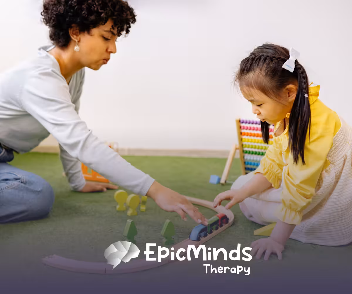 Woman and young girl playing together with a wooden train set on a green play mat in a bright room