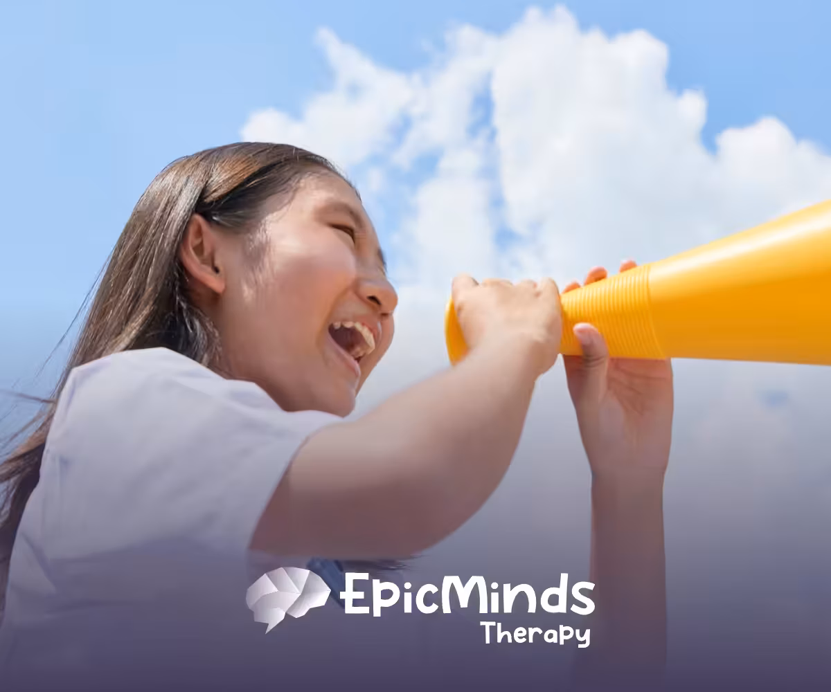 Smiling girl cheering into a yellow megaphone under a blue sky
