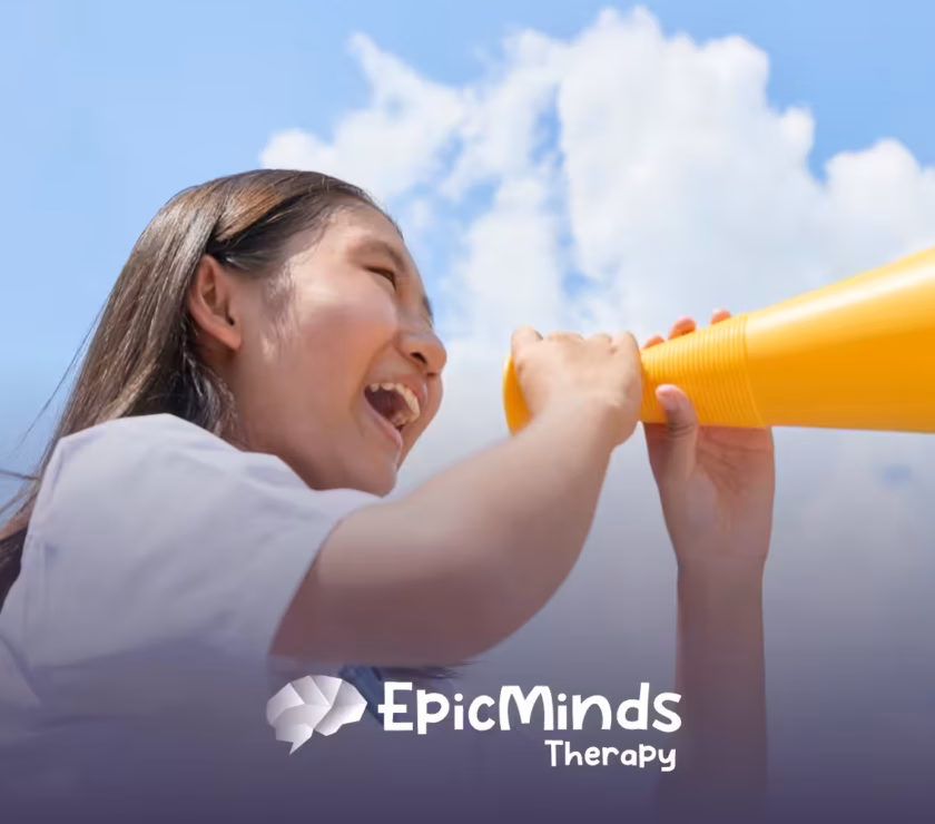 Smiling girl cheering into a yellow megaphone under a blue sky
